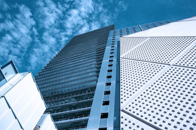Голубое небо отражается в зеркальной стеклянной стене современного здания