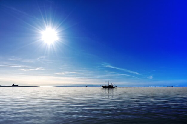 Blue sky and sea near thessaloniki greece sailing boat as a silhouette