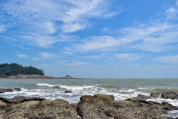 青い空の下で、波はビーチの岩を打ちます