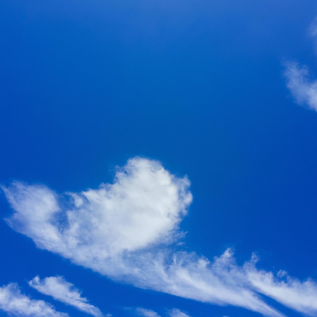 A blue sky with clouds and a heart shaped cloud in the middle