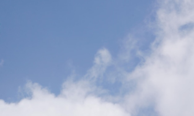 A blue sky with clouds and a red kite in the middle