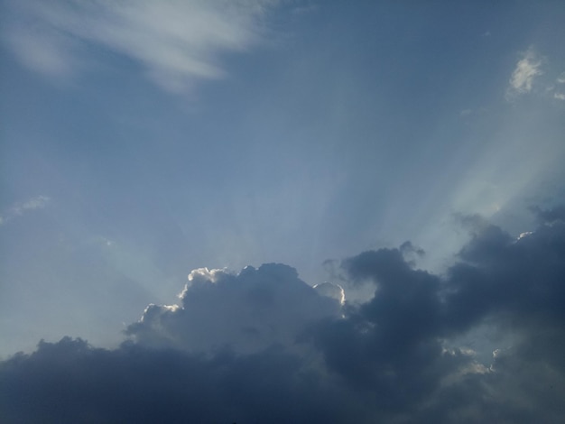 A blue sky with clouds and a sun rays