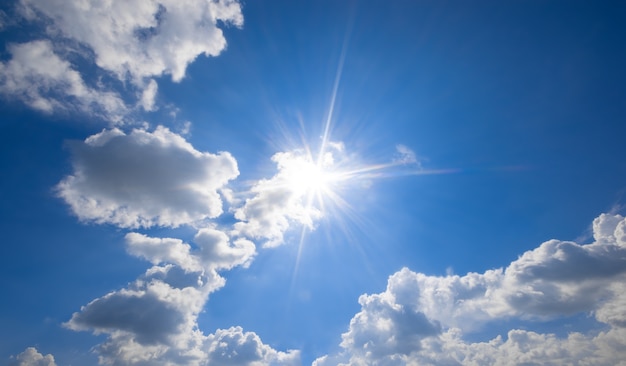 Blue sky with clouds and sun reflection.