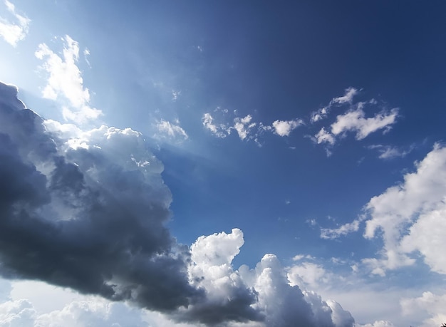 A blue sky with clouds and a sun shining through it