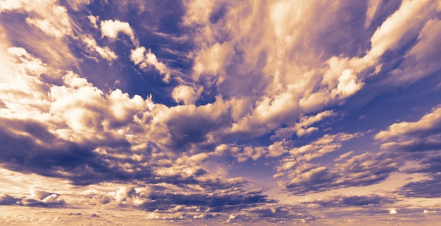 Foto cielo blu con nubi cumuliformi al tramonto.