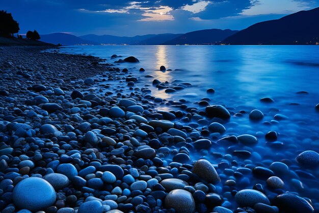 a blue sky with a full moon over a rocky shoreline