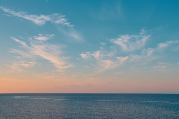 A blue sky with a pink and orange sunset over the ocean