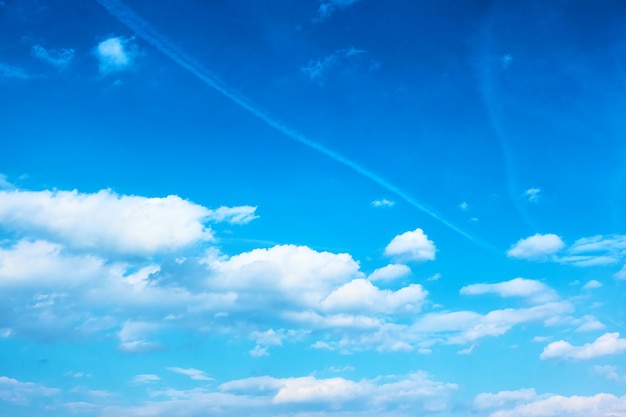 Blue sky with white clouds and plane tracks, may be used as background