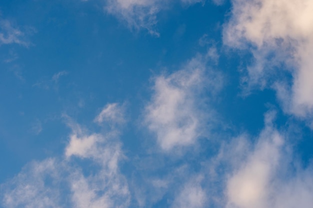 Blue sky with white fluffy glowing clouds. The clouds are lit by the dawn or setting sun. A beautiful natural sky background to replace the sky in your photos