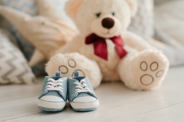 Blue sneakers for baby on the background of soft toys bears, close-up