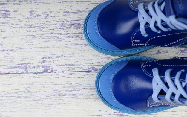 Foto scarpe da ginnastica blu per un bambino su uno sfondo di legno, scarpe per bambini, una copia dello spazio.