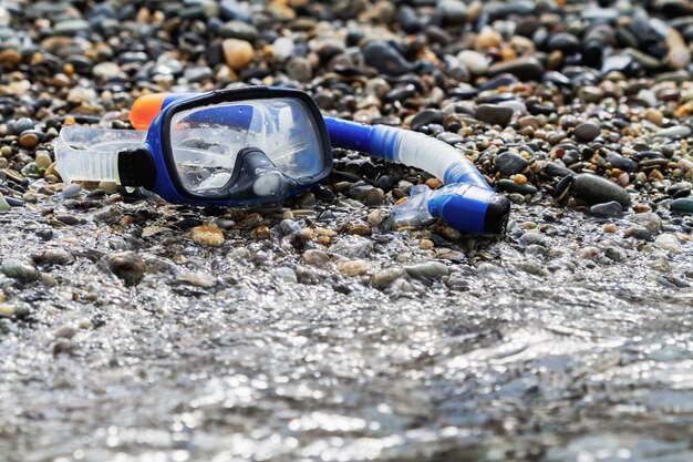 Blue snorkel and mask for diving on the pebble beach