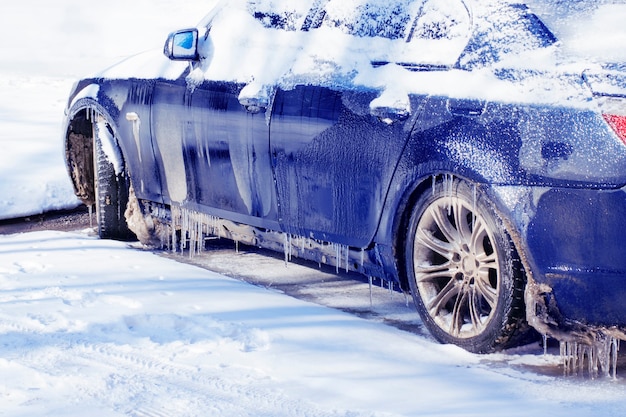 Blue snow-covered car covered with ice.