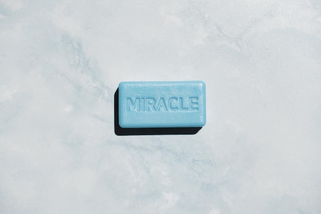 blue soap with shadow with inscription miracle on porcelain tile like marble background