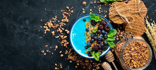 Blue Spirulina and Fresh Fruit Smoothie Bowl Topped with blackberries, blueberries, granola and yogurt. Breakfast. Top view. Free space for your text.