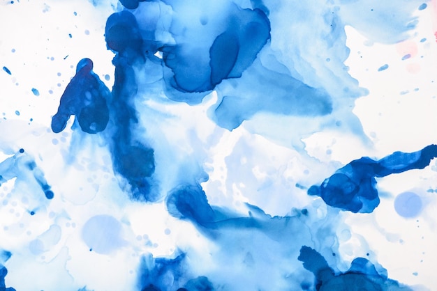 blue splashes of alcohol ink on white as abstract backdrop