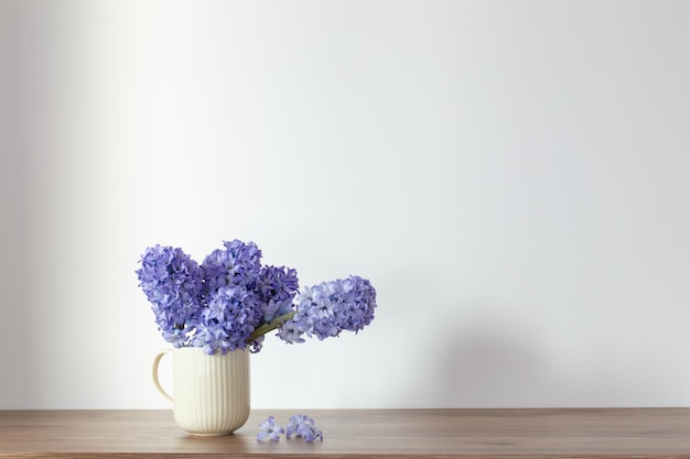 Фото Голубые весенние цветы в керамической чашке на белом фоне