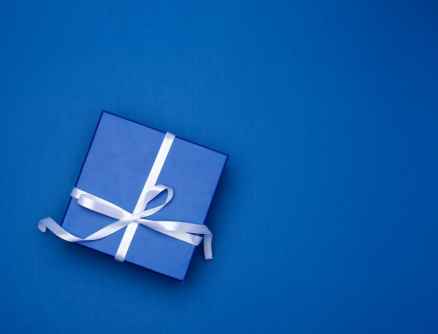 Blue square box with a gift with a bow on a blue classic 