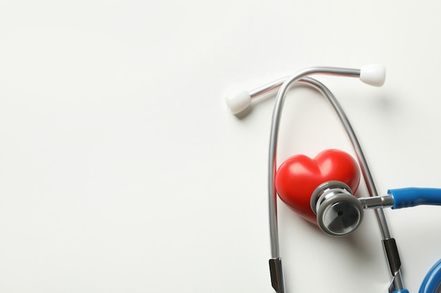 Blue stethoscope and heart on white surface