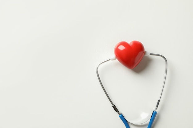 Blue stethoscope and heart on white surface