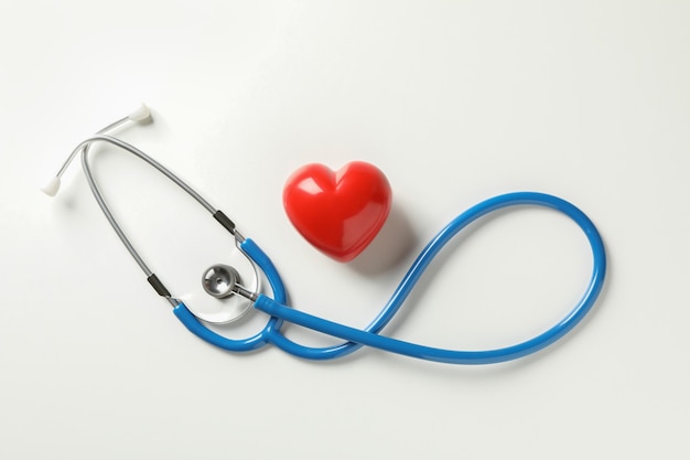 Blue stethoscope and heart on white surface