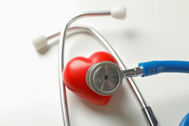 Blue stethoscope and heart on white surface