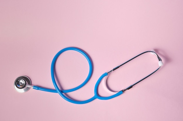 Blue stethoscope on pink surface