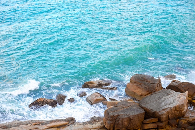 The blue stormy sea beats a wave against the stones water surface seashore top view