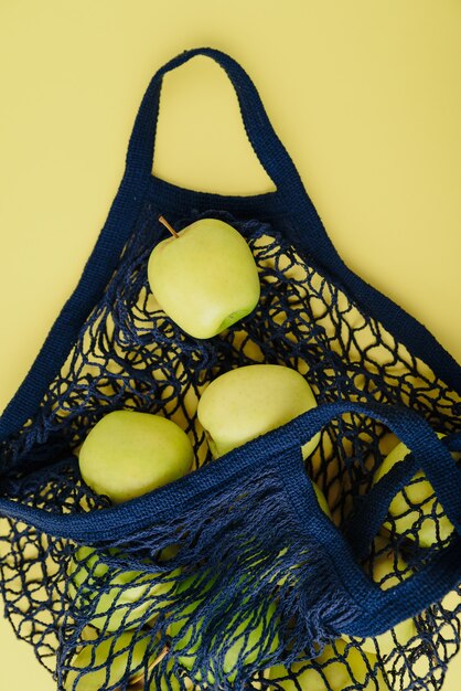 blue string bag with green apples