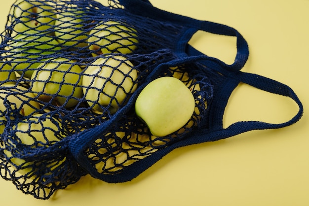 blue string bag with green apples