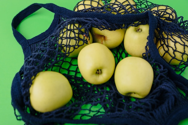 blue string bag with green apples