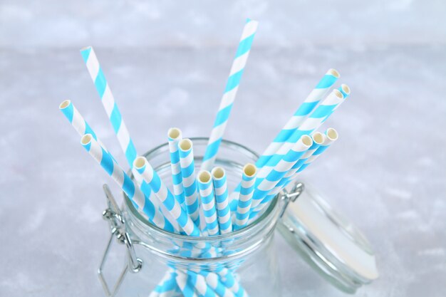 Blue striped paper disposable tubes in a jar on a gray background