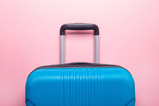 Blue suitcase on pastel pink. Creative Summer holidays, vacation, travel concept