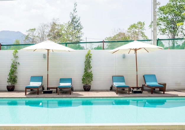 Blue sunbed with white umbrella by the pool water