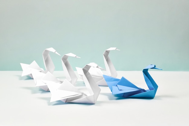 Foto un cigno blu guida uno stormo di cigni bianchi cigni di carta su sfondo blu concetto di leadership di origami