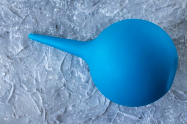 Blue syringe enema pear against the gray background closeup