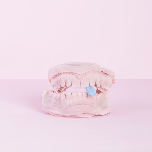 Photo blue tablet inside the dental casting gypsum model plaster cast on pink background