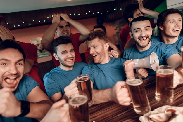 Blue team fans celebrating and cheering in bar.