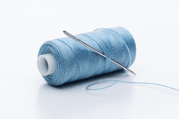 Фото Катушка синей нити с большой иглой для шитья.