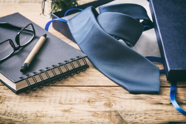 Photo blue tie out of a gift box on a wooden office desk copy space