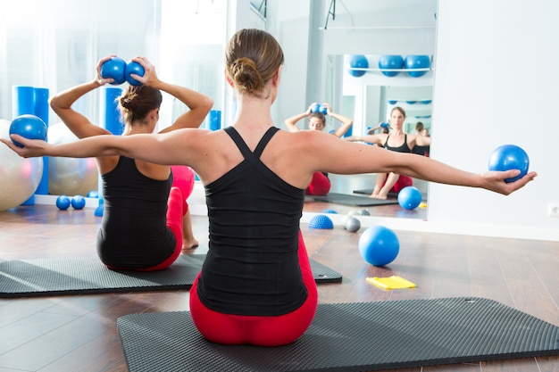  blue toning ball in women pilates class rear view