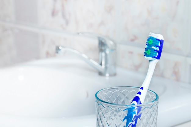 A blue toothbrush in a glass in a bathroom