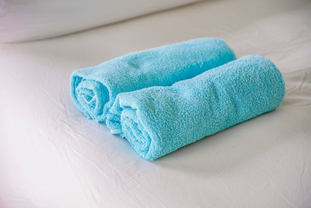 Blue towels on white bed 