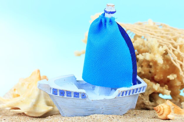 Blue toy ship on sand on blue background