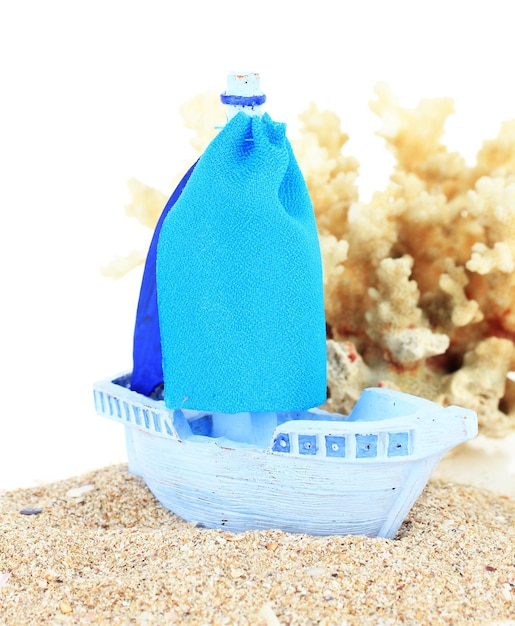 Blue toy ship on sand isolated on white