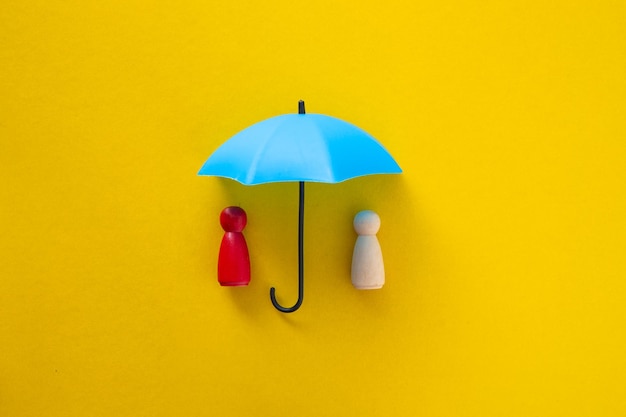 Blue toy umbrella and wooden doll figures insurance coverage concept