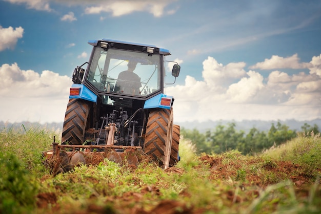 A blue tractor working on farm land 