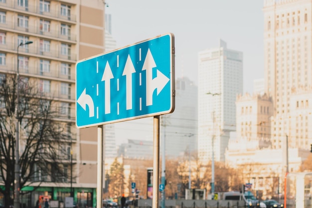 Blue traffic sign indicating rules of turn on the traffic lanes\
and city on the background highway road ride car transportation\
regulations drive driving