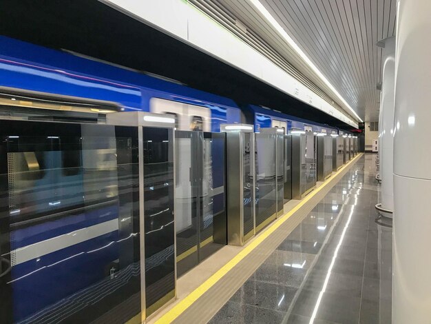 Photo blue train standing with an open sliding mechanical door at a train station platform last