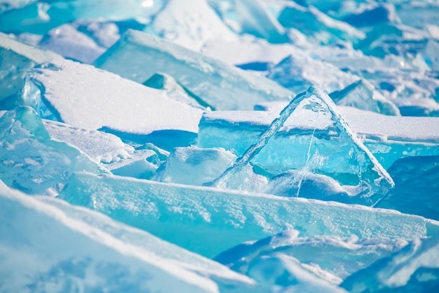 Blue transparent ice with snow on Baikal lake in winter